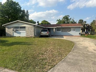 Modest single-story home with a front yard and a concrete driveway leading to an attached garage at 837 Quintilian Ave, Orlando, FL 32809