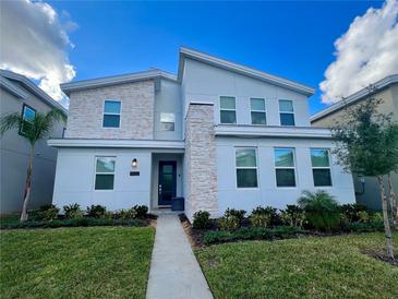 Beautiful modern two-story home with stone facade, manicured lawn, and front entry door at 9122 Sommerset Hills Dr, Davenport, FL 33896