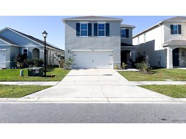Two story home showcasing a long driveway, green shutters, and a well maintained lawn at 1943 Fountains Dr, Kissimmee, FL 34744