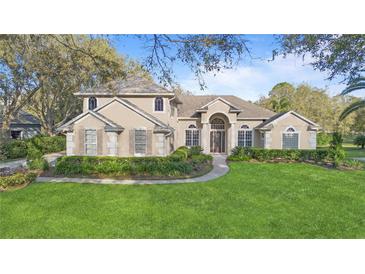 Stately tan two-story home featuring a manicured front lawn and elegant architectural details at 2515 Ridgewind Way, Windermere, FL 34786