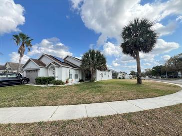 Charming single-story home with palm trees and a well-manicured lawn under a bright blue sky at 2678 Autumn Creek Cir, Kissimmee, FL 34747