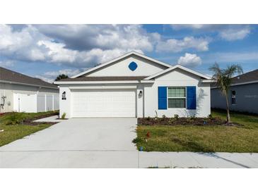 Charming single-Gathering home with a two-car garage, neat landscaping, and vibrant blue shutters at 381 Singing Sands Cir, Lake Wales, FL 33859