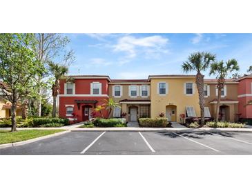 Colorful townhome exterior featuring well-manicured landscaping, a parking lot, and a vibrant facade at 8517 Crystal Cove Loop, Kissimmee, FL 34747