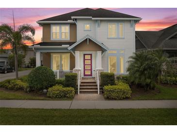 Charming two-story home with landscaped yard, colorful pink entry door, and covered porch at 13831 Briand Ave, Orlando, FL 32827