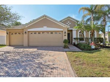Charming single-Gathering home featuring a three-car garage, brick driveway, and lush landscaping at 1502 Fern Bay Ct, Orlando, FL 32824