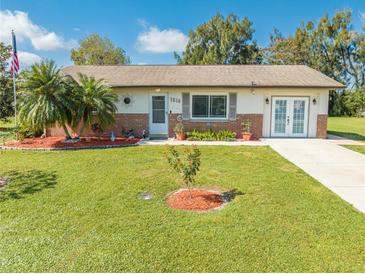 Charming single-story home boasts a lush green lawn, complemented by palm trees and tasteful landscaping at 1518 Mississippi Ave, St Cloud, FL 34769