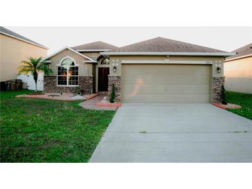 Charming one-story home with a two-car garage, stone accents, lush lawn, and well-manicured landscaping at 2224 Paria Ln, Kissimmee, FL 34758