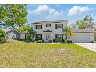 Charming two-story home with a well-manicured lawn, mature landscaping, and a classic white exterior at 4531 Lake Trudy Dr, St Cloud, FL 34769