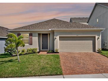Charming single-story home featuring a neutral color scheme, a two-car garage, and a brick paver driveway at 709 Blackstone St, Minneola, FL 34715