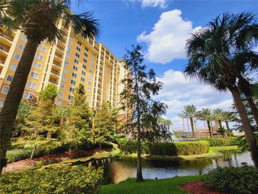 Beautiful condo building with lush landscaping, serene pond, and charming pirate ship feature at 8125 Resort Village Dr # 5310, Orlando, FL 32821