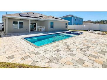 Backyard pool with outdoor kitchen featuring custom stonework and an adjacent outdoor seating area at 152 Big Black Dr, Kissimmee, FL 34759