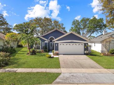Charming single-story home with a manicured lawn and mature landscaping, painted in pleasing, modern colors at 13223 Meadowlark Ln, Orlando, FL 32828