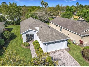 Aerial view of a well-maintained home with a brick driveway and lush green landscaping at 439 Madera Pass, Poinciana, FL 34759