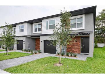 Modern townhome featuring a two-story design, a dark two-car garage, and gray and white color scheme at 4417 Le Reve Ct, Kissimmee, FL 34746