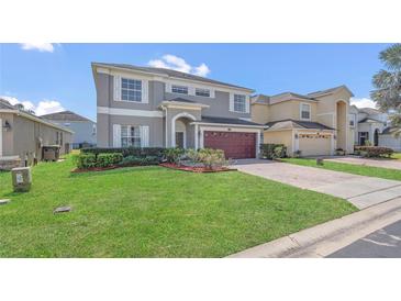 Charming two-story home featuring manicured landscaping and an attached two-car garage, under a sunny sky at 545 Fairhaven Dr, Davenport, FL 33837