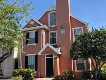Inviting two-story condo showcasing a peach facade, surrounded by lush trees and meticulous landscaping at 9061 Lee Vista Blvd # 1303, Orlando, FL 32829
