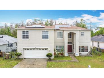 Two-story stucco home with solar panels, attached garage, and covered front entrance at 147 Pompei Dr, Kissimmee, FL 34758