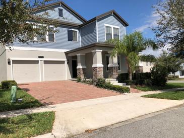 Charming two-story home featuring a brick driveway, two-car garage, and a welcoming front porch with stone accents at 15007 Night Heron Dr, Winter Garden, FL 34787