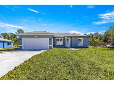 Charming single-story home featuring a manicured lawn, two-car garage, and a light gray stucco finish at 2700 Sw 162Nd St Rd, Ocala, FL 34473
