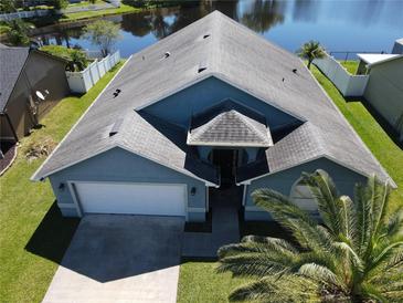 Aerial view of blue home with well-manicured lawn, white fence, and a serene lake view, showcasing curb appeal at 3874 Blackberry Cir, St Cloud, FL 34769