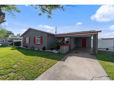 Charming gray single-story home with red trim and an attached carport on a sunny day at 4548 Cepeda St, Orlando, FL 32811