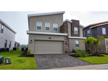 Contemporary two-story home featuring stone accents and a two-car garage at 481 Ocean Course Ave, Davenport, FL 33896