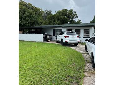 Modest single-story home with a green lawn, carport, and mature trees in a neighborhood setting at 4834 Ute St, Orlando, FL 32819