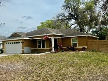 Charming single-story home featuring a well-manicured lawn and an American flag at 74 N Oak Ave, Umatilla, FL 32784