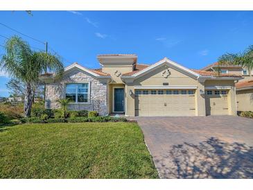 Beautiful single-story home featuring a stone facade, lush lawn, and a spacious two-car garage at 8999 Croquet Ct, Davenport, FL 33896