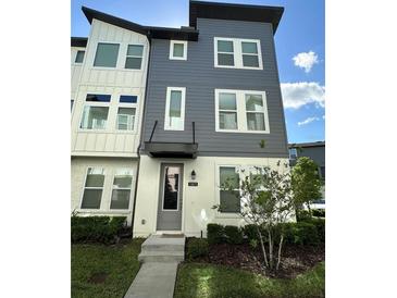 Modern three-story townhome featuring a two-tone exterior and well-manicured landscaping at 12673 Yoshino Aly, Orlando, FL 32827