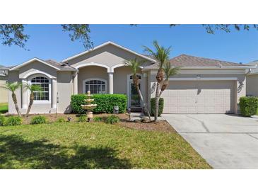 Charming single-story home featuring a well-manicured lawn, lush shrubbery, and a two-car garage at 213 Strathmore Cir, Kissimmee, FL 34744