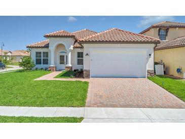 Charming single-story home featuring a red tile roof, arched entryway, and a brick-paved driveway at 362 Villa Sorrento Cir, Haines City, FL 33844