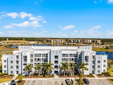 Modern condo building featuring balconies, palm trees, and a view of the lake and other buildings at 4721 Clock Tower Dr # 106, Kissimmee, FL 34746