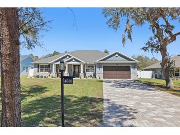 Charming one-story home boasts a well-manicured lawn and a welcoming, covered porch at 4873 Old Oak Trl, St Cloud, FL 34771