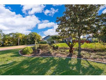 Beautifully landscaped front yard with lush lawn and mature trees leading up to a charming single-story home at 6051 Twin Lakes Dr, Oviedo, FL 32765