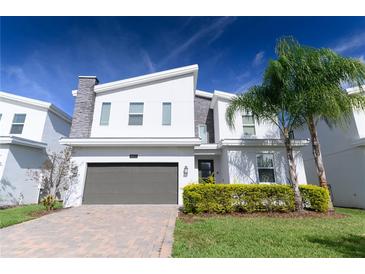 Modern two-story home with gray garage door, decorative stone accents, and well-manicured landscaping under blue skies at 8817 Cruden Bay Ct, Davenport, FL 33896