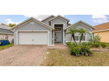 Charming single-story home with a brick driveway, two-car garage, and well-maintained landscaping at 105 Winchester Ln, Haines City, FL 33844