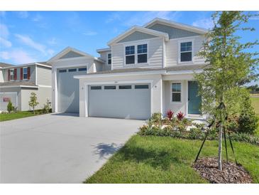 Charming two-story home featuring an attached two-car garage, fresh landscaping, and a welcoming blue front door at 1107 Olivine Ave, Dundee, FL 33838