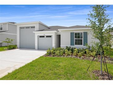 Charming single Gathering home featuring a well manicured lawn, attached two-car garage, and blue shutters at 1122 Olivine Ave, Dundee, FL 33838