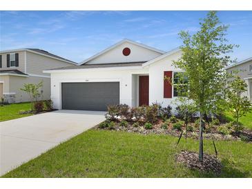 Charming one-story home with a two-car garage, landscaped yard, and white exterior at 1134 Olivine Ave, Dundee, FL 33838