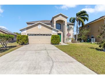 Two-story home with a two car garage, arched window, palm tree, and green door at 417 Spice Ct, Kissimmee, FL 34758