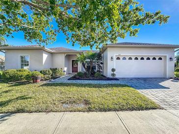 Charming single-story home featuring a manicured lawn, lush landscaping and a brick-paved driveway at 657 Shorehaven Dr, Poinciana, FL 34759