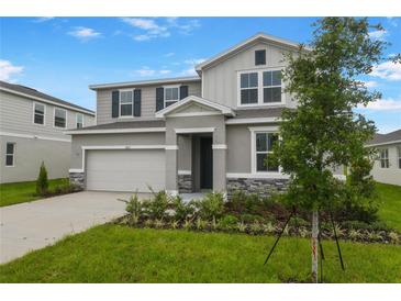 Charming two-story home with stone accents, landscaped yard, and attached two-car garage at 1027 Wisteria Way, Dundee, FL 33838