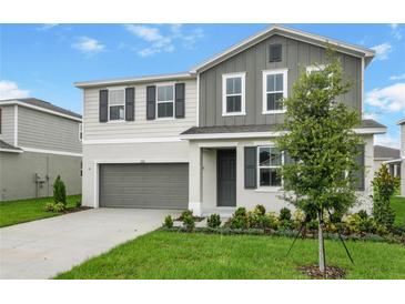 Charming two-story home featuring gray and white colors, a landscaped yard, and a two car garage at 1031 Wisteria Way, Dundee, FL 33838
