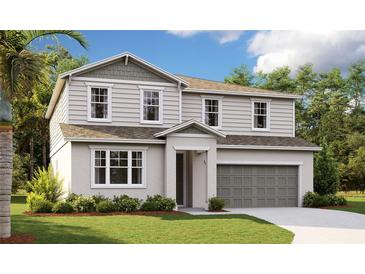 Two-story home showcasing neutral siding, a two-car garage, well-manicured lawn and front garden at 1118 Olivine Ave, Dundee, FL 33838