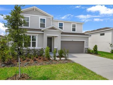 Two-story home with gray siding, stone accents, manicured lawn, and an attached two-car garage in a suburban neighborhood at 1118 Olivine Ave, Dundee, FL 33838