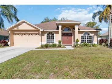 Inviting single-story home featuring a well-manicured lawn, a two-car garage, and a welcoming front entrance at 2706 Sebastian Ct, Kissimmee, FL 34743