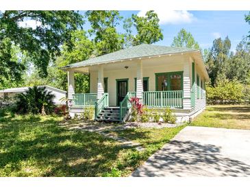 Charming home featuring a covered porch with green railings and a well-maintained front yard and driveway at 5641 Orange Ave, Intercession City, FL 33848