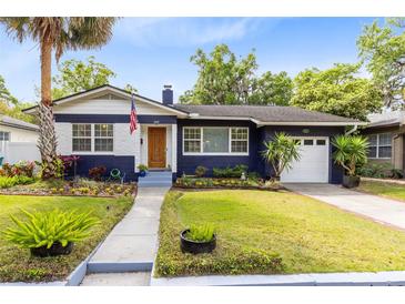 Charming blue home featuring a manicured lawn, blooming flowers, and a welcoming walkway at 1510 E Ridgewood St, Orlando, FL 32803
