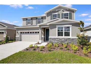 Charming two-story home featuring gray siding, stone accents, and a well-manicured front yard at 2943 Gavin Sky Dr, Kissimmee, FL 34744